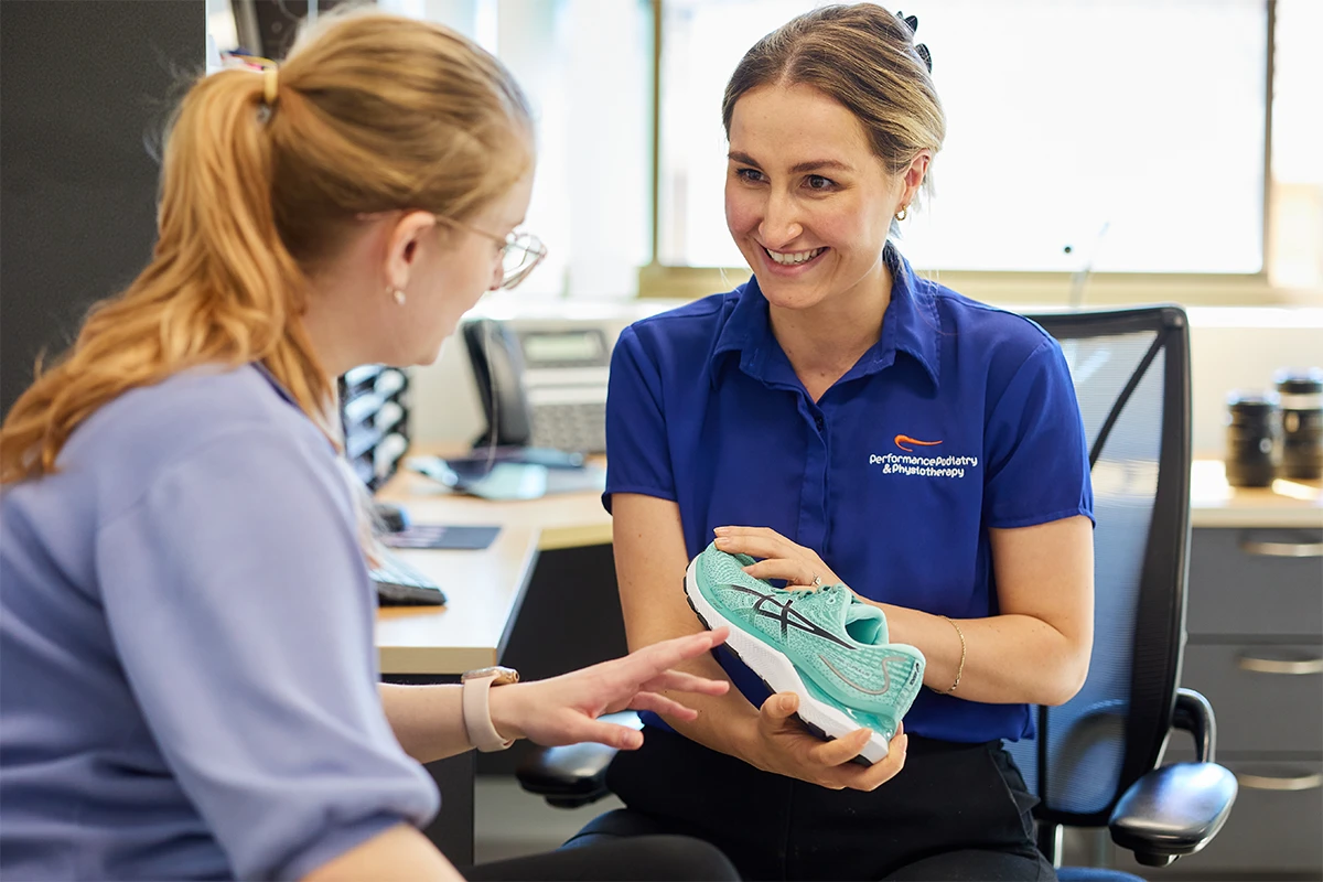 Gemma Parsons, podiatrist at Performance Podiatry explaining footwear to patient